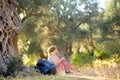 Young woman hiking in countryside. Girl resting under olive tree. Concepts of adventure, extreme survival, orienteering. Royalty Free Stock Photo