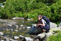 Young woman hiking and having a break by a mountain stream