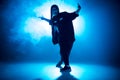 Young woman hip-hop dancer on studio blue light background with flare effects Royalty Free Stock Photo