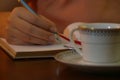 Young woman on his office writing on a book behind a cup Royalty Free Stock Photo