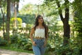 Young woman, Hispanic, beautiful, brunette, with daisy t-shirt and jeans, walking in a park, quiet and lonely. Concept of beauty,