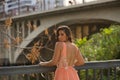 Young woman, Hispanic, beautiful, brunette, wearing an elegant salmon-colored dress, leaning on a railing looking over her Royalty Free Stock Photo