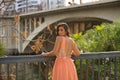 Young woman, Hispanic, beautiful, brunette, wearing an elegant salmon-colored dress, leaning on a railing looking over her Royalty Free Stock Photo