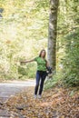 Young woman hitchhiker standing in autumn forest