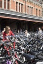 A young woman is hitching her bike, in the middle of a hundred bikes, in the parking of the Amsterdam train station.