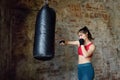 Young woman hits punching bag during a boxing training. Female boxer doing fitness