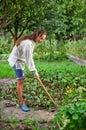 Young woman with hoe working in the garden bed