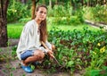 Young woman with hoe working in the garden bed