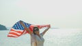 young women hold American flags on the beach and the sea on their summer vacation and they smile and enjoy their vacation Royalty Free Stock Photo