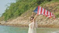 young women hold American flags on the beach and the sea on their summer vacation and they smile and enjoy their vacation Royalty Free Stock Photo