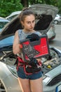 Young woman hold tools for repair and waiting for help near broken car.