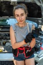 Young woman hold tools for repair and waiting for help near broken car.