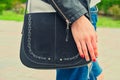 Young woman hold yoyr hand over the black handbag on her shoulder wearing riped jeans