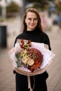 Young woman holding autumn style bouquet of fresh roses, hydrangea , dog-rose, gypsophila and oak leaves