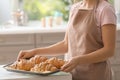 Young woman holding baking tray with fresh croissants indoors Royalty Free Stock Photo