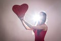 A young woman holding a big red heart against the ligth Royalty Free Stock Photo