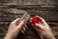 Young woman holding a birth control pills and a condom on wooden background Royalty Free Stock Photo