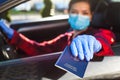 Young woman holding blue passport through car window