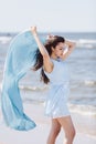 Young woman holding a blue waving scarf.