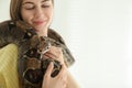 Young woman holding boa constrictor on background, closeup. Exotic pet