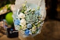 Young woman holding a bouquet of white roses, blue carnation, artificial branches and glittered succulent Royalty Free Stock Photo