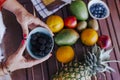 young woman holding a bowl of blackberries. preparing a healthy recipe of diverse fruits, watermelon, orange and blackberries. Royalty Free Stock Photo