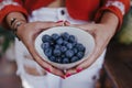 young woman holding a bowl of blueberries. preparing a healthy recipe of diverse fruits, watermelon, orange and blackberries.