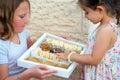 Young Woman Holding A Box With Sweets. Smiling Sweets Vendor Young Girl Hands Food To A Cute Toddler Child. Royalty Free Stock Photo