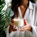 Young woman holding burning candle jar in her hands, container candle mockup closeup shot, mindfulness home interior Royalty Free Stock Photo