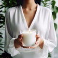 Young woman holding burning candle jar in her hands, container candle mockup closeup shot, mindfulness home interior Royalty Free Stock Photo
