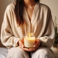 Young woman holding burning candle jar in her hands, container candle mockup closeup shot, mindfulness home interior in Royalty Free Stock Photo