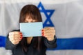 Woman Holding Business Card, Blank Ballot, Voting Paper Front Of Face on Israeli Flag Background. Space for text,mockup. Royalty Free Stock Photo
