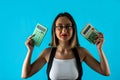 Young woman holding calculator and smiling or wondering isolated on blue background. Royalty Free Stock Photo