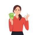 Young woman holding cash or currency or money in hand and showing OKAY or OK sign Royalty Free Stock Photo