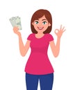 Young woman holding cash/currency/money in hand and showing OKAY sign. Human emotion and body language concept illustration. Royalty Free Stock Photo