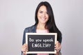 Young woman holding chalkboard that says Do You Speak English?