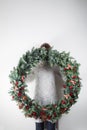 Young woman holding christmas large wreath in hands in light, seasonal holidays, rustic theme, adorning