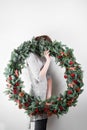Young woman holding christmas large wreath in hands in light, seasonal holidays, rustic theme, adorning