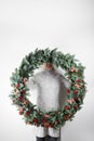 Young woman holding christmas large wreath in hands in light, seasonal holidays, rustic theme, adorning