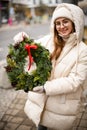 Young woman holding Christmas wreath decorated with pine cones and red ribbon Royalty Free Stock Photo