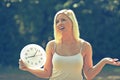 Young woman holding clock and pointing it by finger Royalty Free Stock Photo