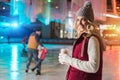 young woman holding coffee to go while her family skating behind