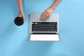 Young woman holding coffee while using laptop on blue background, top view Royalty Free Stock Photo