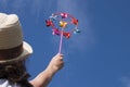 Young woman holding colorful bright rainbow toy pinwheel against blue sky Royalty Free Stock Photo