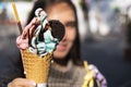 Young woman is holding colorful soft serve ice cream in cone.