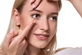 Young woman holding contact lens on index finger with copy space. Close up face of healthy beautiful woman about to wear Royalty Free Stock Photo