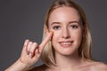 Young woman holding contact lens on index finger with copy space. Close up face of healthy beautiful woman about to wear Royalty Free Stock Photo