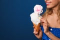 Young woman holding cotton candy dessert on blue background, closeup Royalty Free Stock Photo