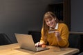 Young woman holding credit card and using laptop computer. Businesswoman or entrepreneur working from apartment. Online shopping, Royalty Free Stock Photo