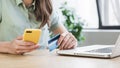 Young woman holding credit card and using laptop computer. Businesswoman or entrepreneur working in office. Royalty Free Stock Photo